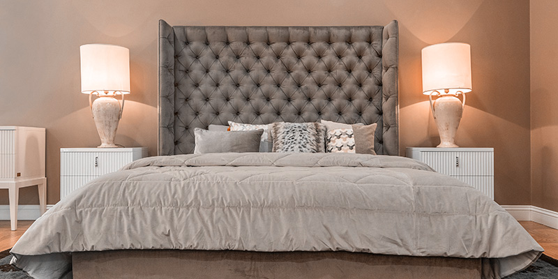 Beautiful bed with lamps on nightstands on both sides of the bed.