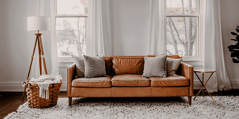 Couch and floor lamp in a dimply lit room.